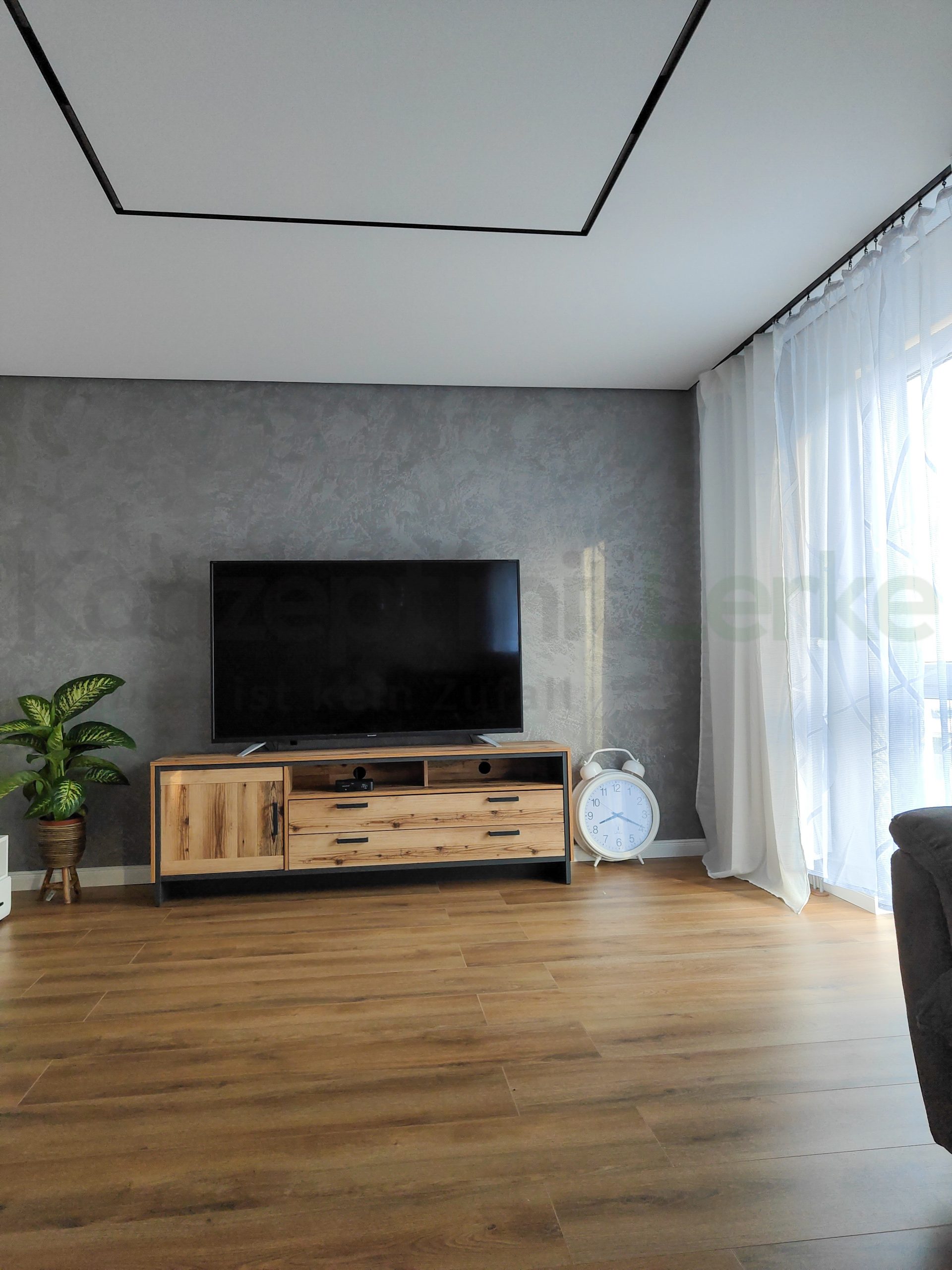 Wohnzimmer mit weißer Spanndecke und schwarzem, rechteckig angeordnetem Lichtsystem mit einzelnen Leuchtelementen.