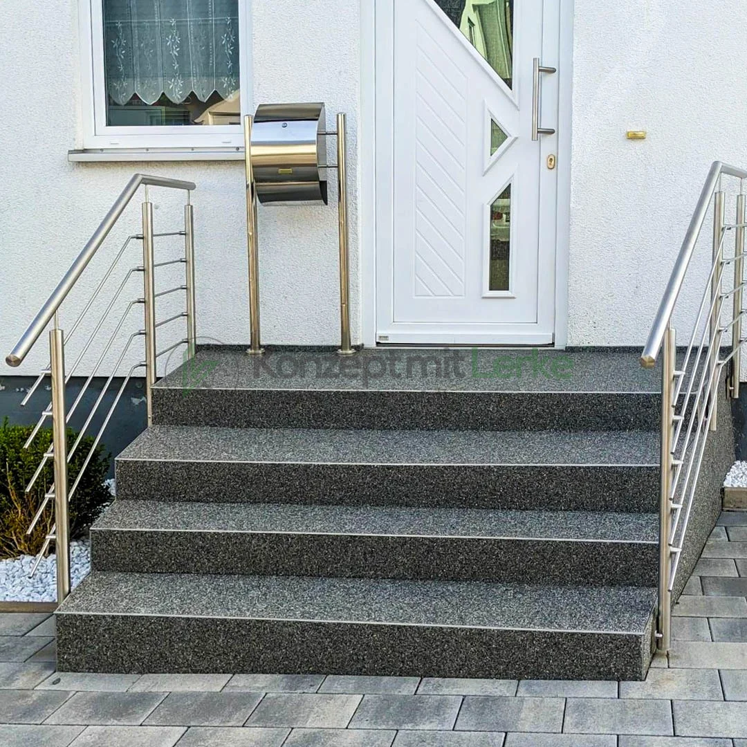 Außentreppe mit grauem Steinteppich und angrenzendem Eingangsbereich eines modernen Wohnhauses.