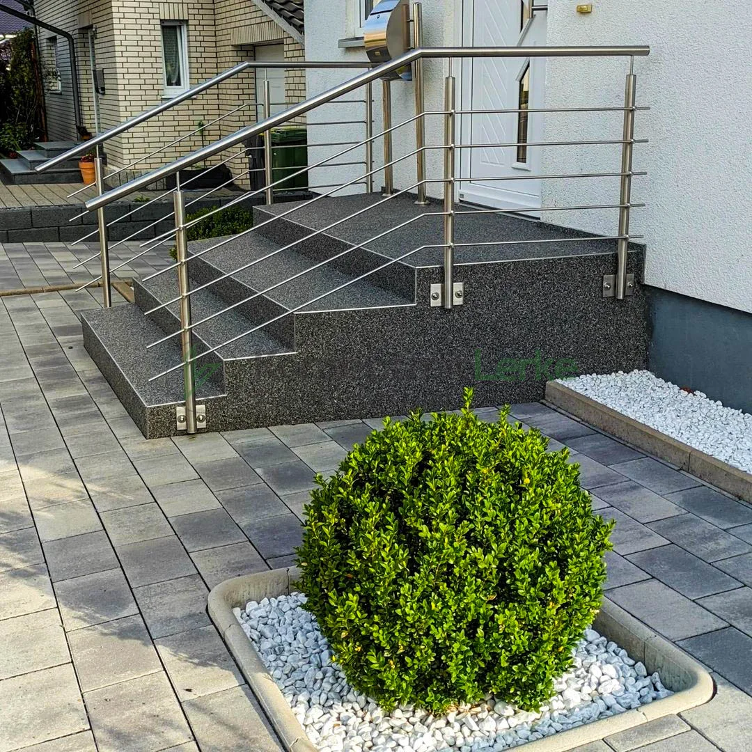 Außentreppe mit grauem Steinteppich und angrenzendem Eingangsbereich eines modernen Wohnhauses.